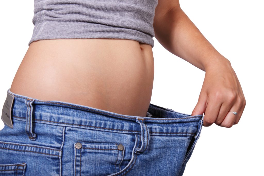 Woman pulling out the waistband of her pants, experiencing perimenopause bloating without a period."